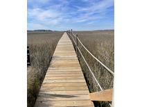 Scenic boardwalk view with wooden planks and rope railing over a beautiful field landscape against a blue sky with clouds at 2119 Landfall Way, Seabrook Island, SC 29455
