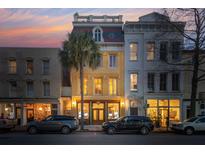 Charming townhouse featuring a unique colorful roof, inviting exterior lighting, and lush palm tree at 29 Broad St # A C, Charleston, SC 29401