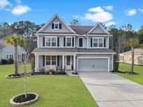 Charming two-story home with manicured lawn, two-car garage, and inviting front porch at 502 Pontoon Rd, Huger, SC 29450