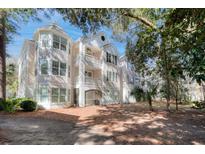 Beautiful exterior shot of a multi-level condo with balconies and attractive architectural design, surrounded by mature trees at 60 Fenwick Hall Aly # 622, Johns Island, SC 29455