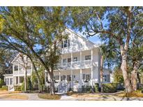 Charming two-story white home with a double porch, nestled among mature trees at 610 Daggett St, Daniel Island, SC 29492