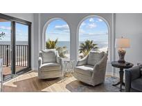 Comfortable living room with two chairs overlooking beach and ocean views from large arched windows at 9002 Palmetto Drive #514 1/13 Share, Isle of Palms, SC 29451