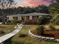Charming brick home featuring a landscaped front yard, walkway, and manicured shrubbery at 11 Boardman Rd, Charleston, SC 29407