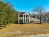 Charming two-story brick home featuring a columned front porch and a well-manicured lawn on a sunny day at 1401 Cooper River Blvd, Moncks Corner, SC 29461
