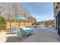 Inviting backyard pool area with chaise lounges and an umbrella providing shade and relaxation at 146 Stagecoach Ave, Summerville, SC 29486
