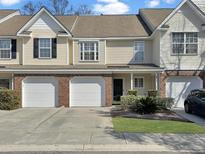 Attractive townhome showcasing a two-car garage, brick accents, and manicured landscaping at 8715 Grassy Oak Trl, North Charleston, SC 29420