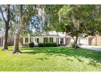 Charming single-story brick home with a lush, green front yard and mature trees covered in Spanish moss at 108 Nightingale Manor, North Charleston, SC 29418