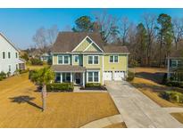 Charming two-story home with green siding, well-manicured lawn, and two car garage at 136 Stagecoach Ln, Summerville, SC 29483