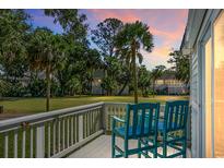 Charming balcony view with teal chairs overlooking lush lawn and mature palm trees, creating a serene outdoor space at 278 Driftwood Ln, Edisto Island, SC 29438