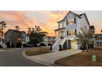 Charming two-story home with a welcoming front porch and beautiful landscaping at sunset at 482 Sanders Farm Ln, Charleston, SC 29492