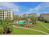 Beautiful community pool surrounded by lush landscaping, palm trees, and upscale resort-style buildings at 8000 Palmetto Dr # 506, Isle of Palms, SC 29451