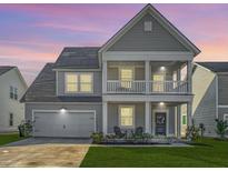Charming two-story home with a double front porch and a well-manicured lawn at twilight at 185 Red Bluff St, Summerville, SC 29483