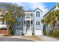 Charming two-story beach home featuring a double front porch, light blue siding, and dual garage doors at 27 Ocean Point Dr, Isle of Palms, SC 29451