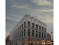 Stunning white corner building with arched windows, set against a dramatic, cloudy sky at 71 Wentworth St # 302, Charleston, SC 29401