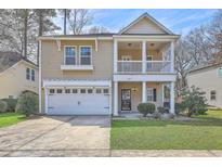 Charming two-story home boasts a welcoming porch, a well-manicured lawn, and an attached two-car garage at 8475 Athens Way, North Charleston, SC 29420