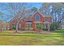 Charming two-story brick home with manicured lawn and mature trees under a sunny blue sky at 8614 Arthur Hills Cir, North Charleston, SC 29420