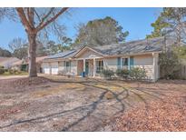 Charming single-story home featuring solar panels, a well-manicured lawn, and a welcoming front porch at 204 Mohican Cir, Summerville, SC 29483