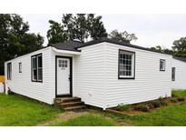 Charming home featuring white siding, black trim, brick steps and well-maintained landscaping at 2121 Cosgrove Ave, North Charleston, SC 29405