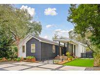 Striking home showcasing a dark-stained wood siding, with a paved driveway and mature landscaping at 2166 Welch Ave, Charleston, SC 29412