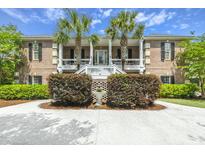 Charming brick home with a double porch, palm trees, manicured hedges, and a fountain at 221 Indigo Bay Cir, Mount Pleasant, SC 29464