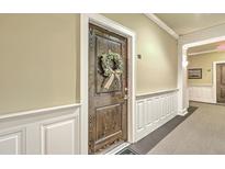 Unit's front door with wreath, located in a hallway with wainscoting, and neutral walls at 2244 Ashley Crossing Dr # 224, Charleston, SC 29414