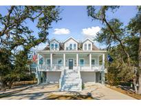 Charming two-story home featuring a double front porch, white railings, and a ground-level garage at 2514 Bullock Guard Dr, Johns Island, SC 29455