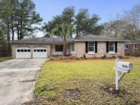 Charming brick home with a well-maintained lawn, mature trees and a two-car garage at 4341 Helene Dr, North Charleston, SC 29418