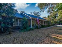 Charming single story home with an American flag on the front porch and mature trees in the front yard at 731 Fort Johnson Rd, Charleston, SC 29412