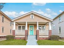 Charming bungalow featuring a quaint front porch with brick accents and a vibrant turquoise door at 774 Rutledge Ave, Charleston, SC 29403