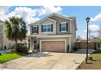 Charming two-story home featuring tan siding, green shutters, and an attached two-car garage at 7753 Kinston St, North Charleston, SC 29418