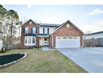 Charming two-story brick home featuring a manicured front yard and attached two-car garage at 103 Hartland Ln, Goose Creek, SC 29445