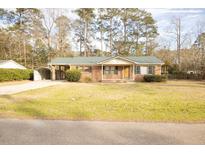 Charming brick home featuring a metal roof, carport, and spacious front yard at 105 Pinewood St, Walterboro, SC 29488