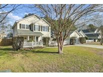 Charming two-story home featuring a picket fence, lush lawn and mature trees at 147 Moon Dance Ln, Summerville, SC 29483