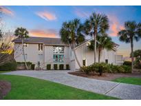 Stunning coastal home with a spacious driveway, lush lawn, and mature palm trees at 2238 Catesbys Blf, Seabrook Island, SC 29455