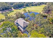 An aerial view showcases the house backing up to a golf course and a pond surrounded by lush green trees at 31 Berkshire Hall, Kiawah Island, SC 29455