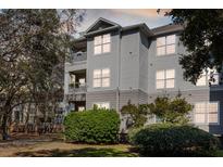 Three-story condominium with gray siding, balconies, manicured bushes, and a well-maintained lawn at 700 Daniel Ellis Dr # 5302, Charleston, SC 29412