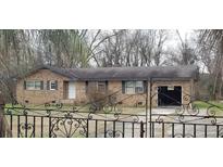 Charming brick home features an attached garage and a decorative wrought iron fence, with mature trees surrounding the property at 1097 Murrell Block Dr, Pineville, SC 29468