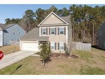 Charming two-story home with a manicured front yard and attached garage. The house has neutral siding and dark shutters at 122 Rockingham Way, Moncks Corner, SC 29461
