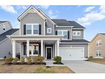 Charming two-story home with gray siding, black shutters, covered front porch and two car garage at 234 Evergreen Ave, Summerville, SC 29485