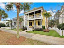 Charming yellow two-story home with double porches, lush landscaping, and a white picket fence at 2876 Rivertowne Pkwy, Mount Pleasant, SC 29466