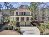 Inviting two-story home featuring double garages, a spacious porch, and a long driveway nestled among tall trees at 3575 Holmgren St, Mount Pleasant, SC 29466