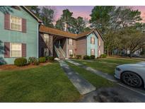 Inviting condo complex featuring a covered stairwell entrance, green lawn and convenient parking at 7930 Timbercreek Ln # C, North Charleston, SC 29418