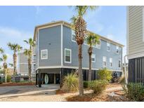 Coastal home featuring a raised foundation, blue siding, and palm trees adding a touch of tropical charm at 9 J C Long Blvd, Isle of Palms, SC 29451