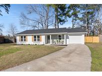 Charming single-story home featuring a well-manicured lawn and a long driveway leading to an attached garage at 105 Gippy Dr, Summerville, SC 29486