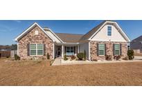 Charming single-story home featuring a stone facade, landscaped front yard, and covered porch at 121 Lakelyn Rd, Moncks Corner, SC 29461