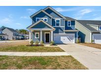 Charming two-story home featuring a covered porch, attached garage and manicured lawn at 130 Whisper Dr, Summerville, SC 29485