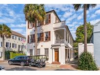 Stately multi-story home showcasing a beautiful facade, private golf cart, mature palm trees, and a blue sky backdrop at 38 State St # 2, Charleston, SC 29401