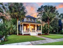 Charming two-story home with a welcoming front porch, lush lawn, and beautiful palm trees at sunset at 4057 E Amy Ln, Johns Island, SC 29455