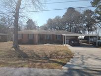 Charming brick ranch-style home with a well-maintained lawn and covered parking at 102 Hamlet Ln, Ladson, SC 29456