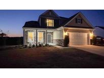 Charming two-story home featuring a stone facade, covered porch with rocking chairs, and an attached two-car garage at 123 Lakelyn Rd, Moncks Corner, SC 29461